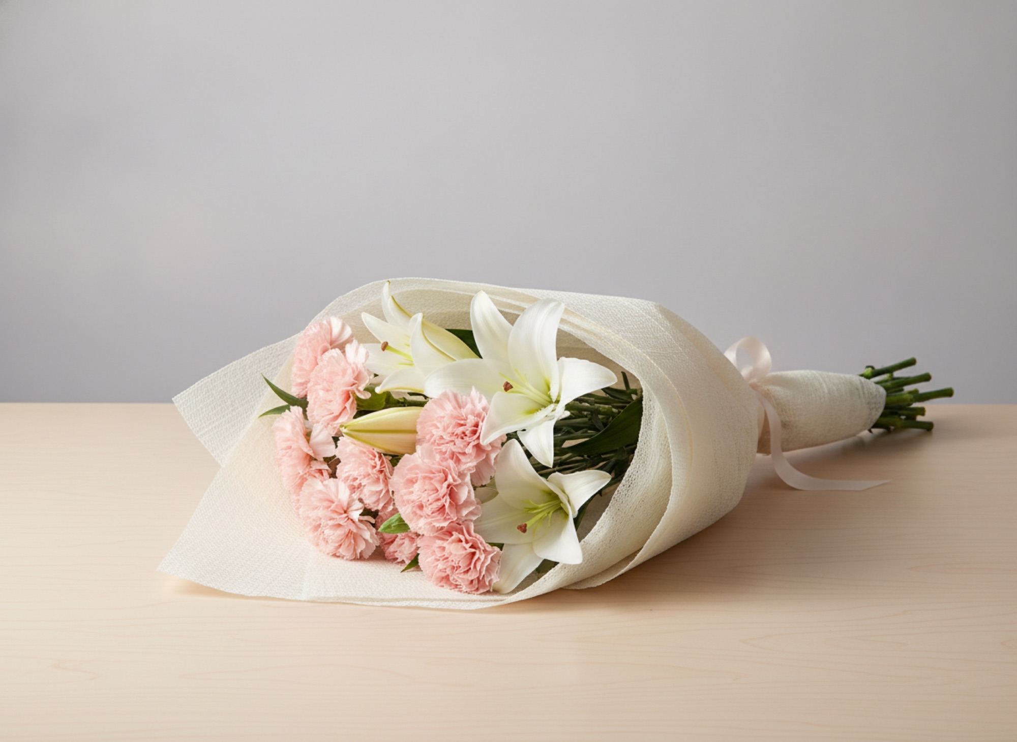 粉紅康乃馨配白百合的花束，米色包裝紙